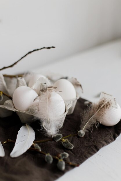 Stylish Easter still life Natural eggs in tray feathers willow branches on rustic table