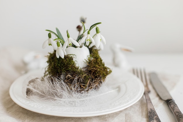 Stylish Easter table setting Natural egg snowdrops nest modern plate napkin cutlery bunny