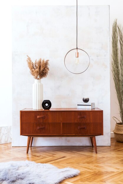 Stylish and eclectic interior of living room with design retro cabinet, round pendant lamp, marble cubes and elegant accessories. Minimalistic home decor. Copy space.