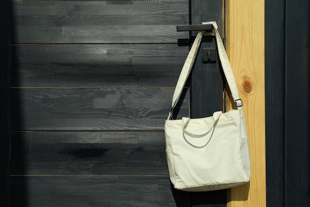 Stylish eco bag hanging on the doorknob, space for text