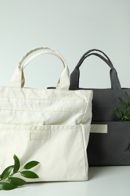 Stylish eco bags and twigs on white background