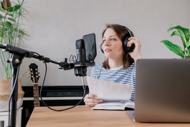 The stylish and educated caucasian woman records podcasts in a recording studio or in her home the