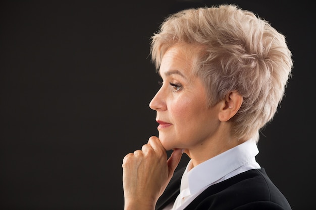 stylish elderly woman with a short haircut in a black suit