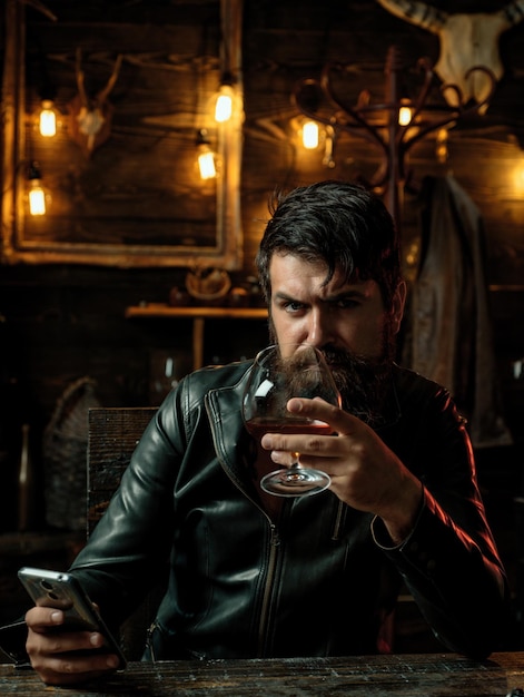 Stylish elegant bearded man holds whiskey glass social media addiction alcohol abuse