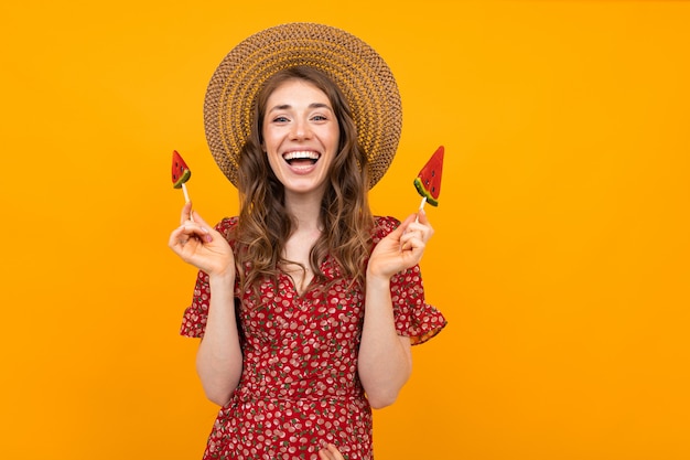 Stylish european girl with watermelon lollipops on a yellow background