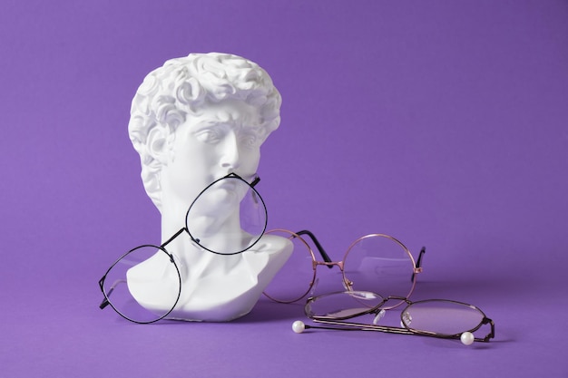 Стильные очки с гипсовой скульптурой на фиолетовом модном цветном фоне, копия пространства дэвида бюста