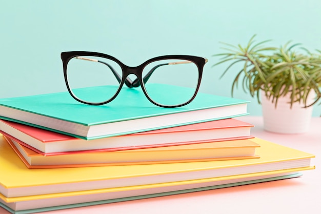 Stylish eyeglasses over pile of books. studing, reading, optical store, eye test, vision examination at optician, fashion accessories concept. front view