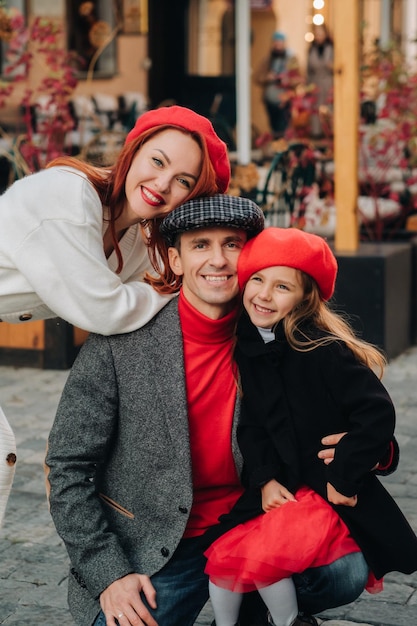 A stylish family of three strolls through the autumn city posing for a photographer Dad mom and daughter in the autumn city