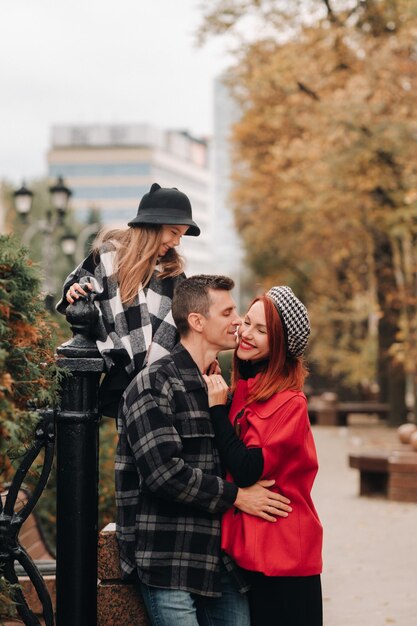 A stylish family of three strolls through the autumn city posing for a photographer Dad mom and daughter in the autumn city