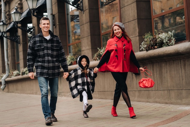 A stylish family of three walks in the city in autumn holding hands