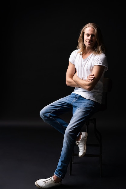 Stylish fashion man model sitting on the chair isolated on black