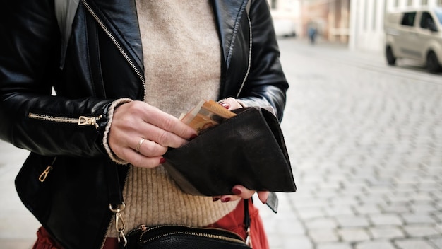 Stylish female counts euro cash money in wallet on city street