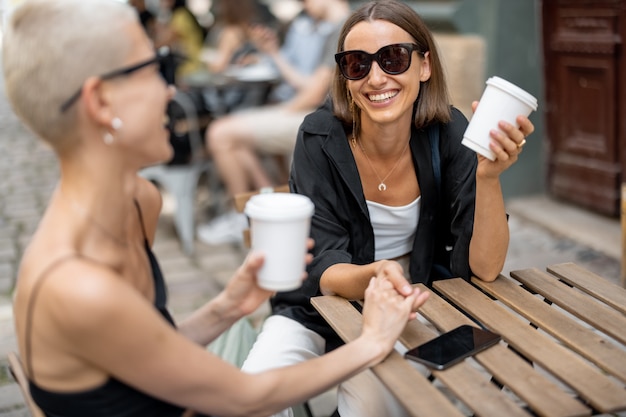 屋外のカフェテラスでスタイリッシュな女性のカップル