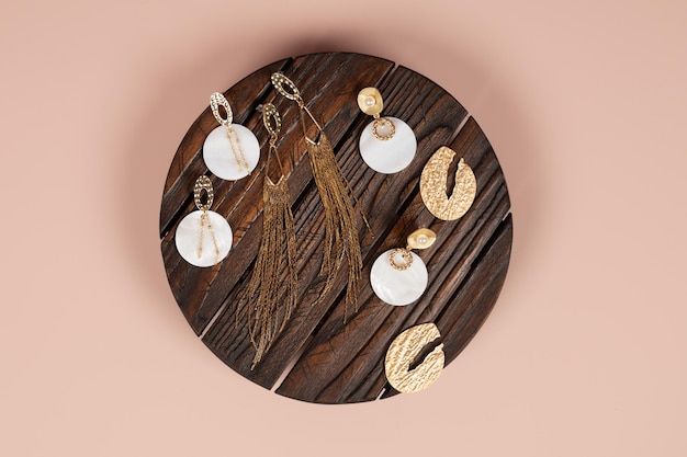 Stylish female jewelry on a dark textured wooden background Top view of golden glamorous earrings