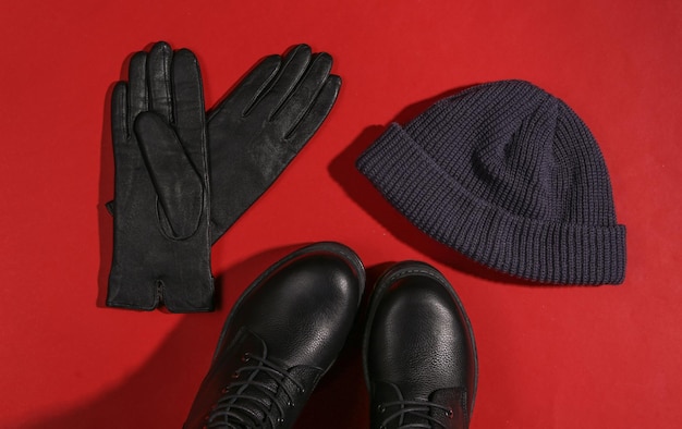 Photo stylish female leather boots with high soles hat and gloves on red background with a shadow top view