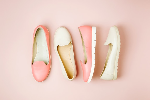 Stylish female shoes in pastel colors on pastel pink background, top view