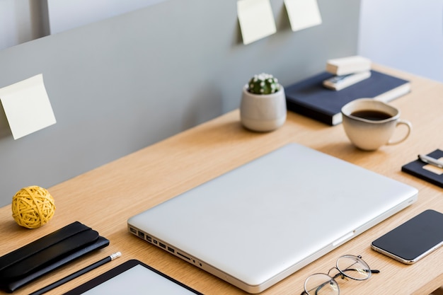 Stylish flat lay business composition on the wooden desk with laptop, tablet, mobile screen, cacti, cup of coffee, notes and office supplies in modern concept.