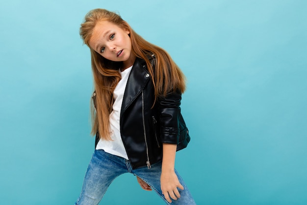 Photo stylish girl in a casual look with a leather jacket and jeans on light blue