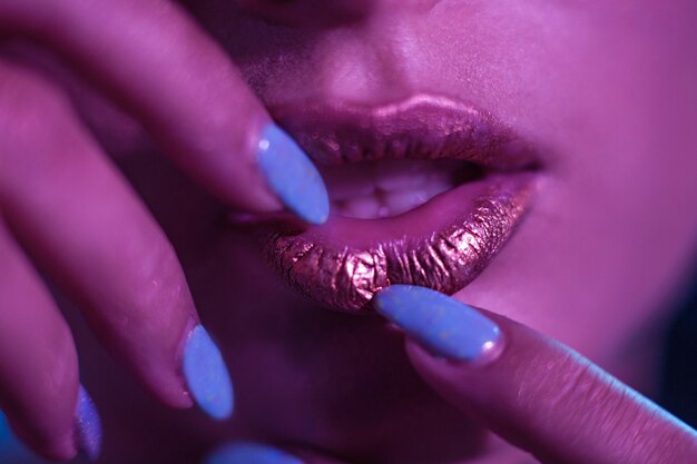 Photo stylish girl model with golden lips and bright nails.