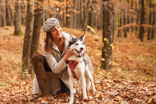 stylish girl playing with her husky dog in the autumn forest