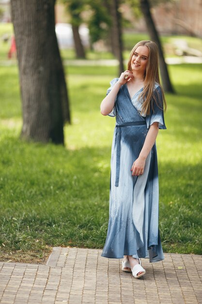 Stylish girl posing in a dress in a sunny spring park