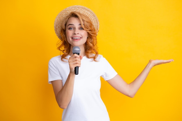 Stylish girl singing songs with microphone holding mic at karaoke posing against yellow background