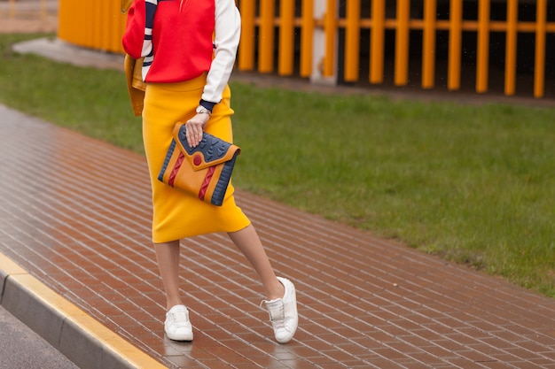 Стильная девушка стоит на улице в ярко-желтой одежде