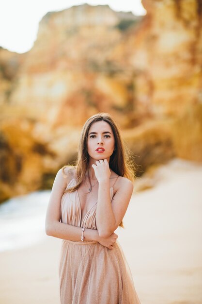 stylish girl standing with flying hair from the wind at sunset on the beach and the ocean