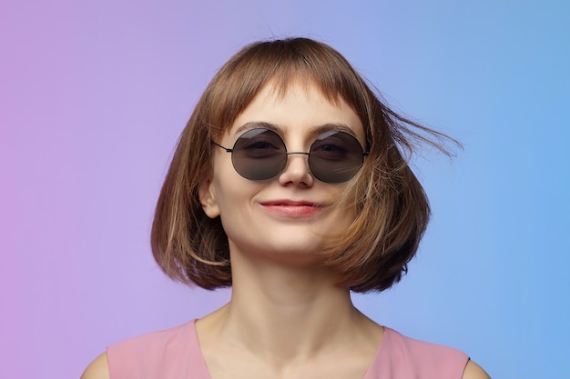 Stylish girl in sunglasses. photo shoot in the studio on a pink background