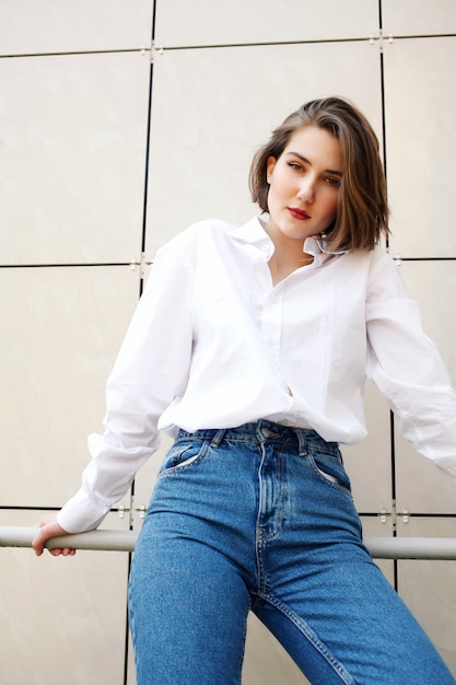 Photo stylish girl in vintage jeans and white shirt