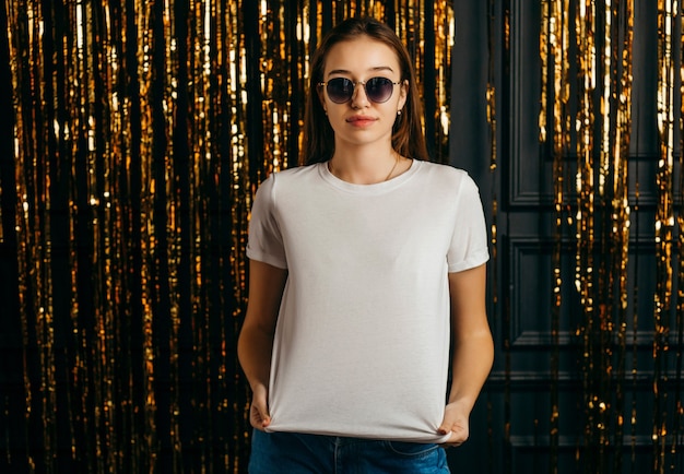 Stylish girl wearing white t-shirt and sunglasses posing in studio