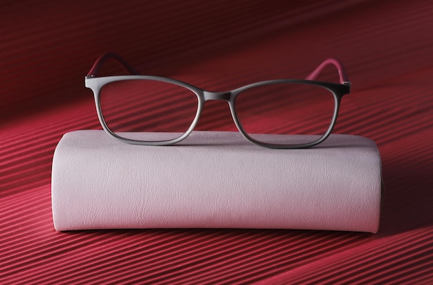 Photo stylish glasses for eyesight with elegant black grey on red background classic frame