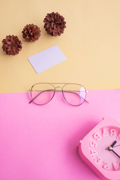 Stylish glasses over pastel background. Business Card, Pastel Pink And Yellow Colors. Alarm Clock, Fir Tree Flowers.