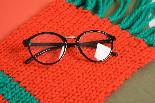 Stylish glasses on red knitted scarf, christmas style concept