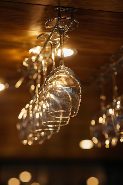 Stylish glasses for various alcoholic beverages hang over the bar in a modern restaurant Glasses for wine champagne