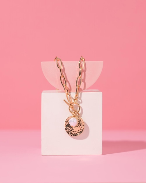 Stylish gold jewelry rings and necklace with different design on a pink background