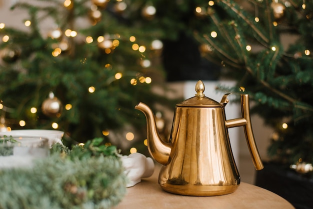 Stylish gold vintage teapot on the table against the background of Christmas lights