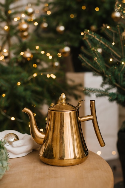 Stylish gold vintage teapot on the table against the background of Christmas lights