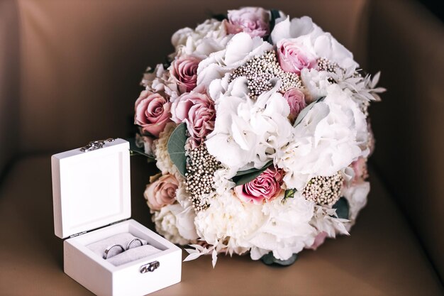 Stylish gold wedding rings in a box and a modern bouquet on the table