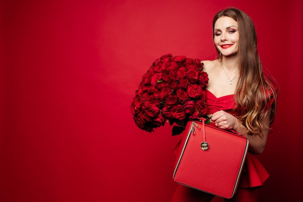 Stylish gorgeous brunette in red with red roses and red bag