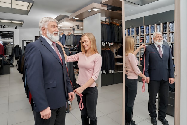 Stylish grandfather in suit standning in front of mirror