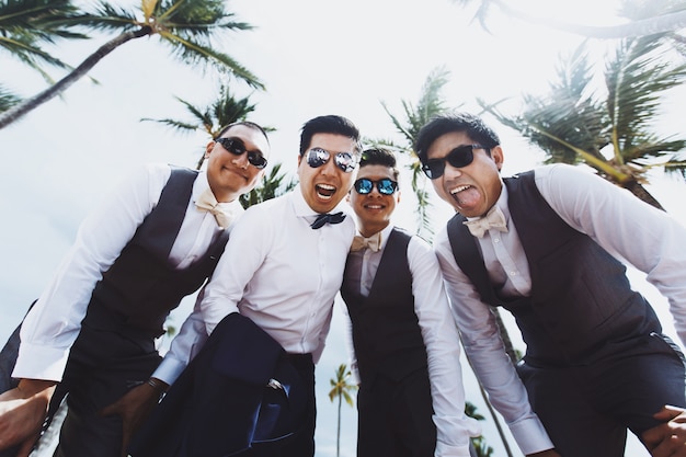 Photo stylish groom and groomsmen pose under tall green palms