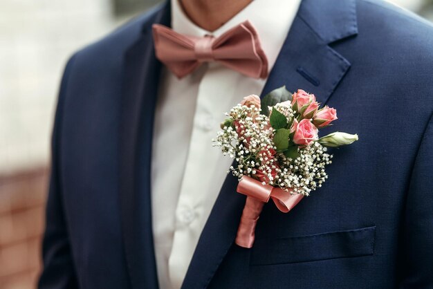 Foto elegante sposo o groomsmen in abito con rose rosa fiore all'occhiello e papillon in posa prepararsi al mattino per la cerimonia di nozzexa