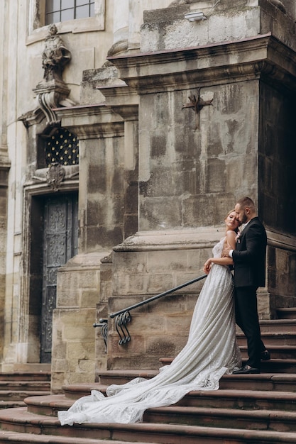 Stylish groom hugs from behind beautiful bride