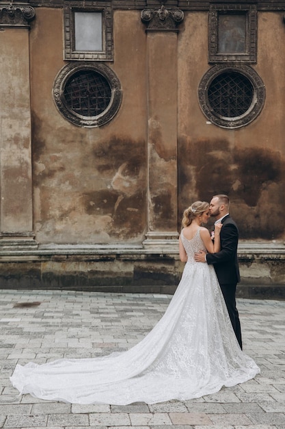 Stylish groom hugs from behind beautiful bride