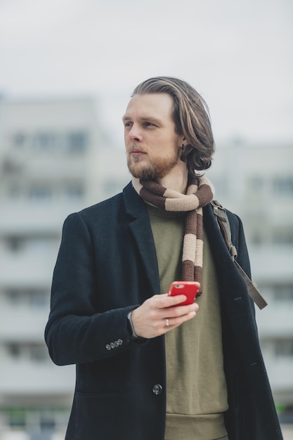 Stylish guy in scarf and coat hold mobile phone in a hand at street of Wroclaw Poland