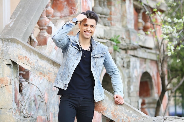 Stylish guy standing street in a denim jacket against men's looks