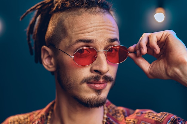 Stylish guy with dreadlocks wearing pink sunglasses close up