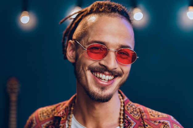 Stylish guy with dreadlocks wearing pink sunglasses close up