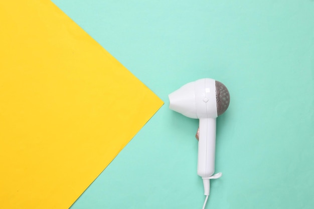 Photo stylish hair dryer on yellow blue paper background minimalism fashion layout top view copy space